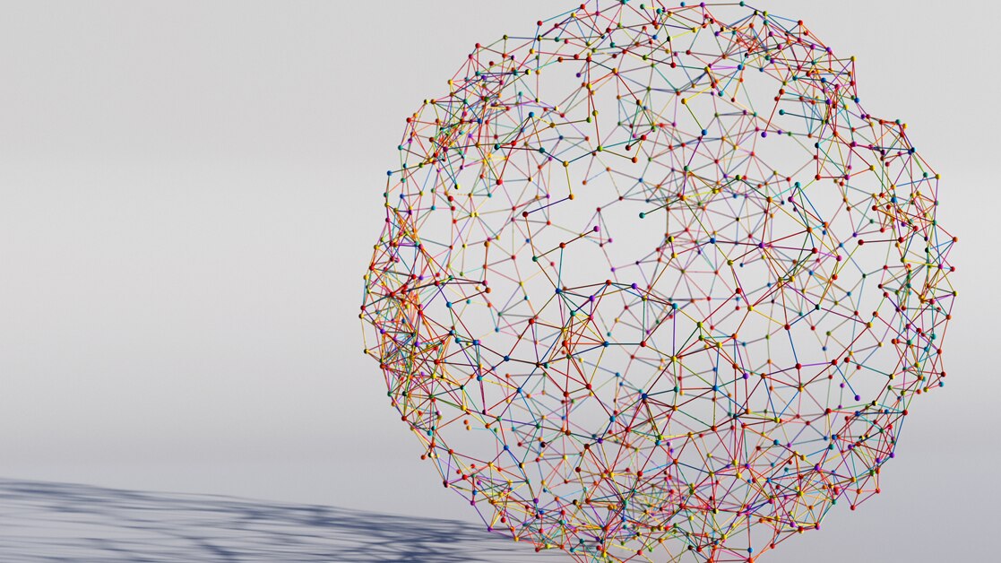 Multi-colored globe made from connected sticks, resting on a white background